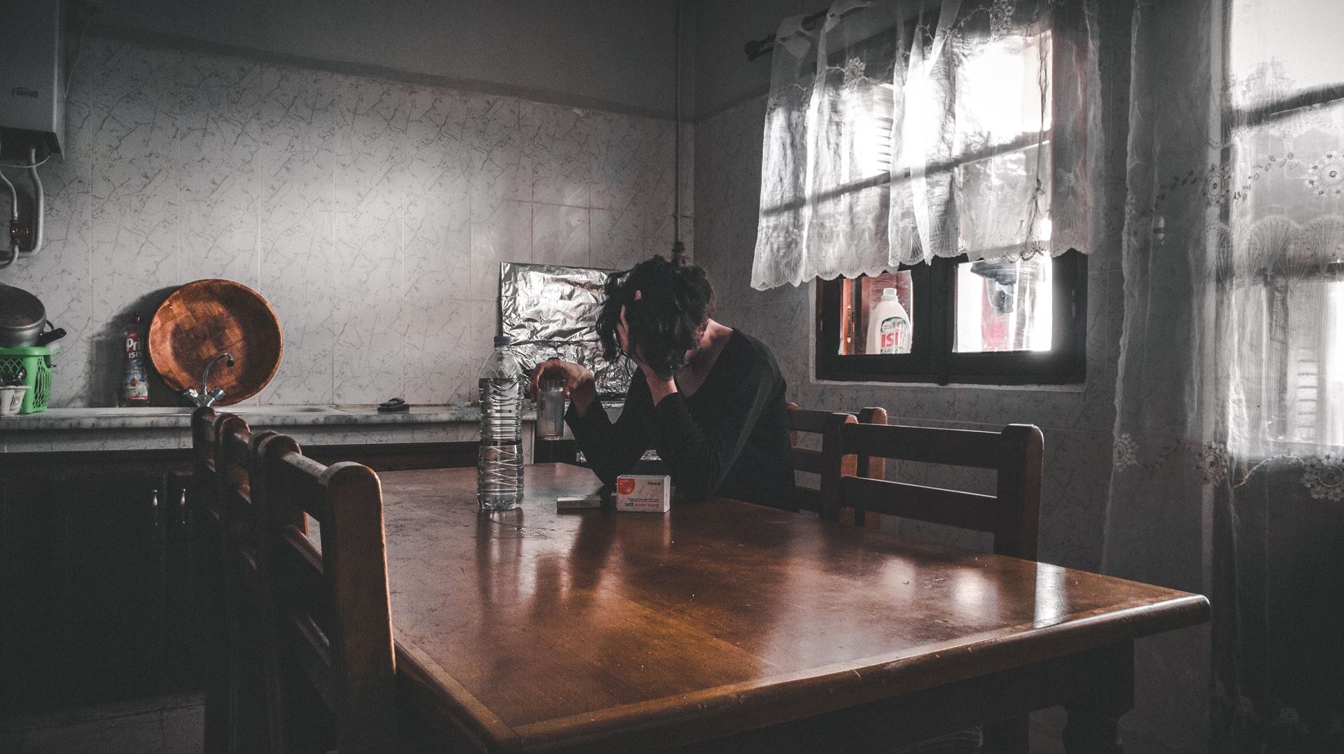 a person sitting at a table in a kitchen